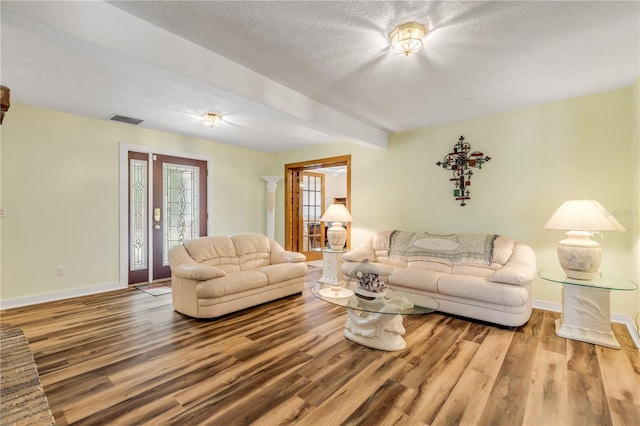 living room with wood-type flooring, a textured ceiling, and beam ceiling