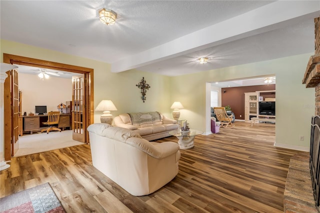 living room with beam ceiling, a textured ceiling, and light wood-type flooring