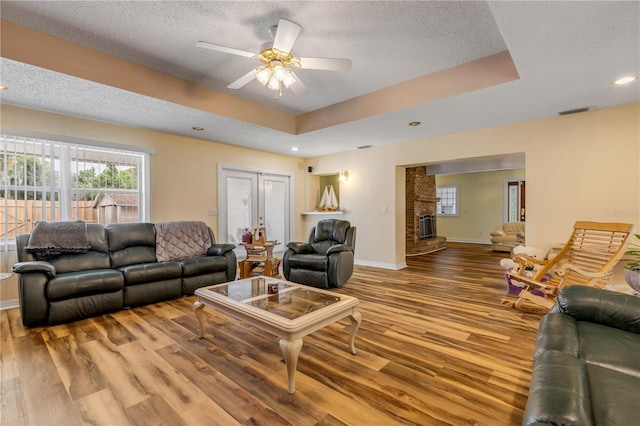 living room featuring a tray ceiling, hardwood / wood-style floors, and a textured ceiling