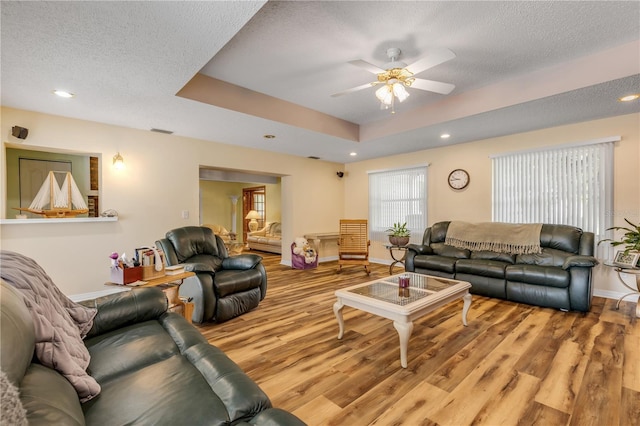 living room featuring wood-type flooring, a textured ceiling, and ceiling fan