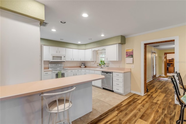 kitchen with white cabinetry, light wood-type flooring, white appliances, and crown molding