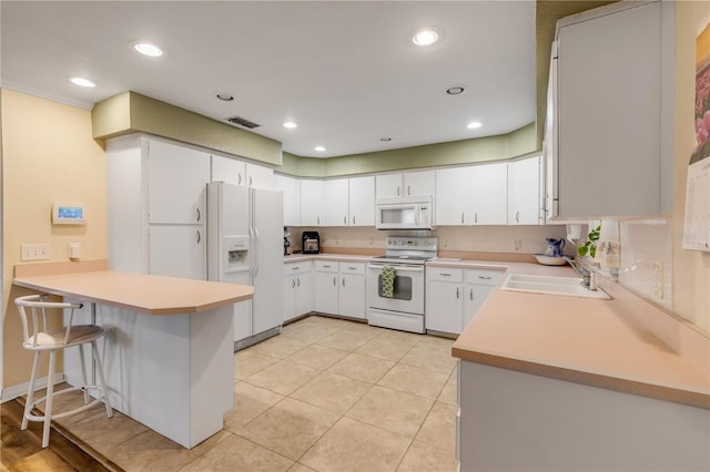 kitchen with kitchen peninsula, white appliances, white cabinetry, and sink