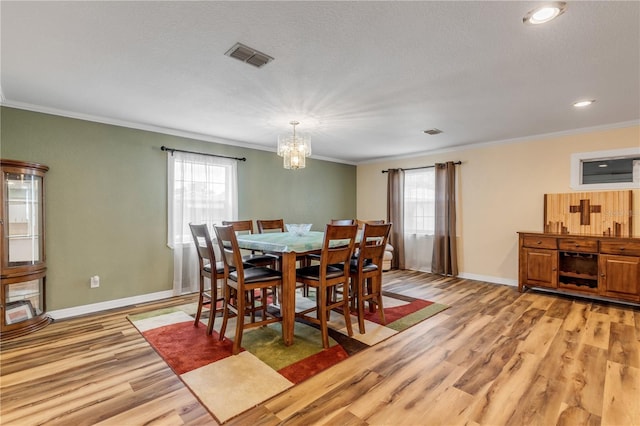 dining room with crown molding, plenty of natural light, and light hardwood / wood-style flooring