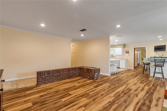 empty room featuring a textured ceiling, light hardwood / wood-style floors, and crown molding