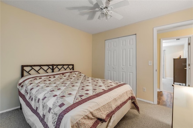 carpeted bedroom featuring ceiling fan, a closet, and a textured ceiling