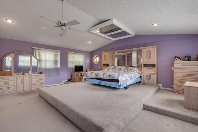 carpeted bedroom featuring a textured ceiling, ceiling fan, multiple windows, and vaulted ceiling