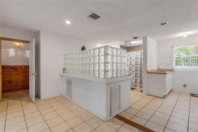 kitchen with light tile patterned flooring, kitchen peninsula, and a textured ceiling