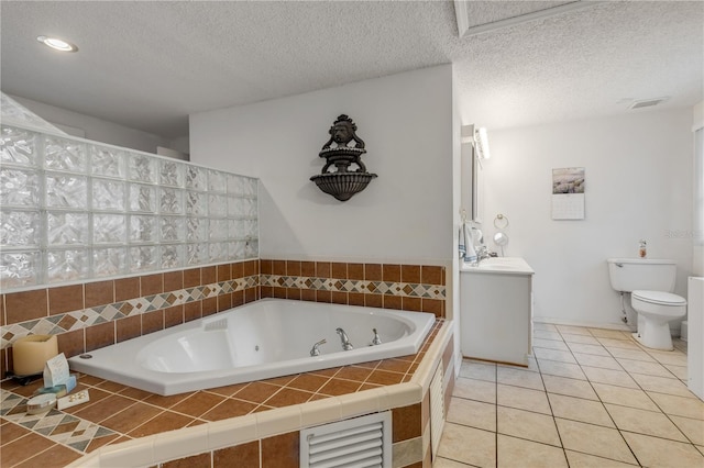 bathroom featuring vanity, a textured ceiling, tile patterned flooring, tiled bath, and toilet