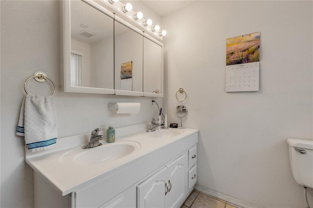 bathroom with tile patterned flooring, vanity, a textured ceiling, and toilet