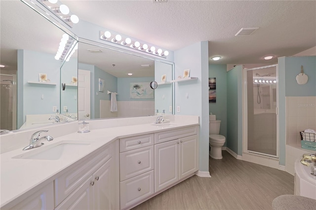 bathroom with vanity, a shower with door, hardwood / wood-style flooring, toilet, and a textured ceiling