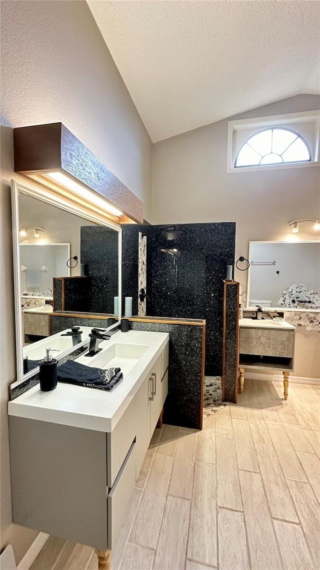 bathroom with vaulted ceiling, vanity, and a textured ceiling