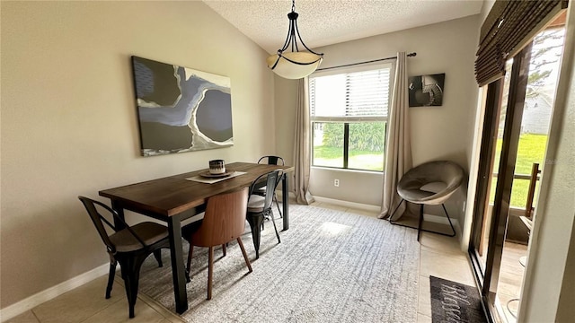 dining area with vaulted ceiling, light tile patterned floors, and a textured ceiling