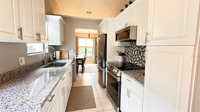 kitchen with white cabinets, sink, light tile patterned floors, and appliances with stainless steel finishes