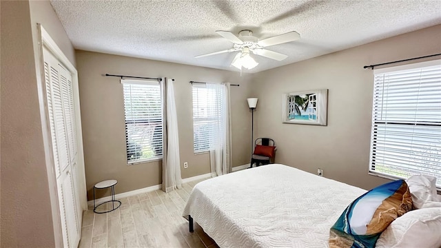 bedroom featuring a textured ceiling, ceiling fan, light hardwood / wood-style flooring, and a closet