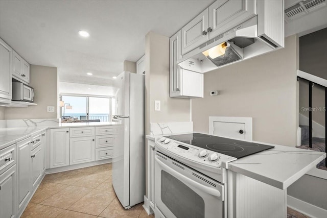 kitchen with kitchen peninsula, premium range hood, white appliances, light tile patterned floors, and white cabinets