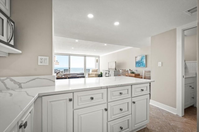 kitchen featuring light stone counters, white cabinetry, and light tile patterned floors