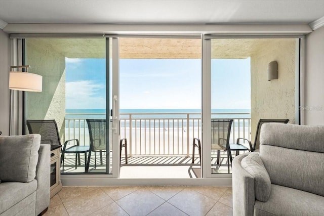 living area with a view of the beach, a water view, and a wealth of natural light