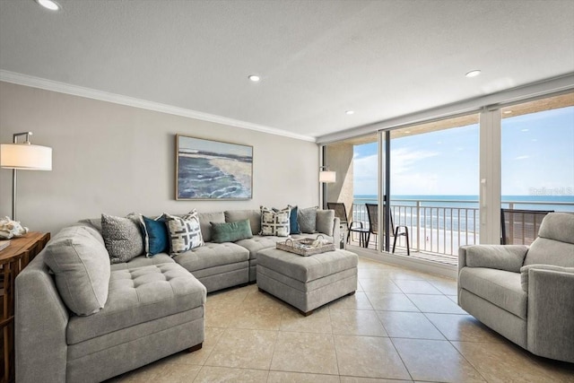 tiled living room with crown molding, a water view, a beach view, and a wall of windows