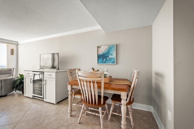 dining area with wine cooler, ornamental molding, and light tile patterned flooring