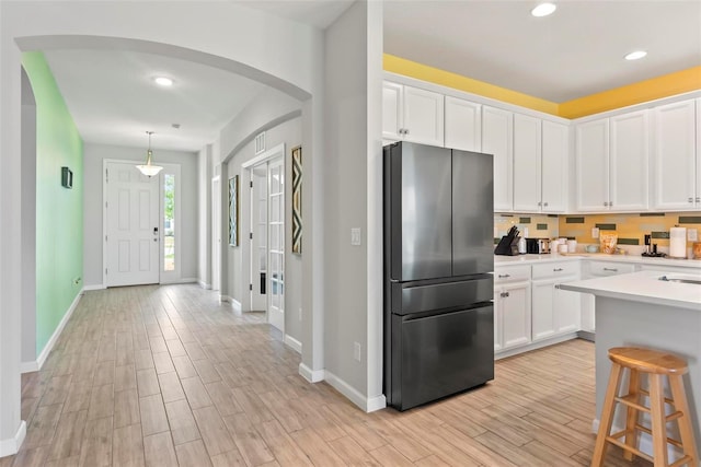 kitchen with decorative light fixtures, a kitchen breakfast bar, white cabinetry, and stainless steel refrigerator