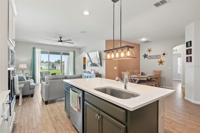 kitchen with white cabinets, a center island with sink, sink, decorative light fixtures, and stainless steel appliances