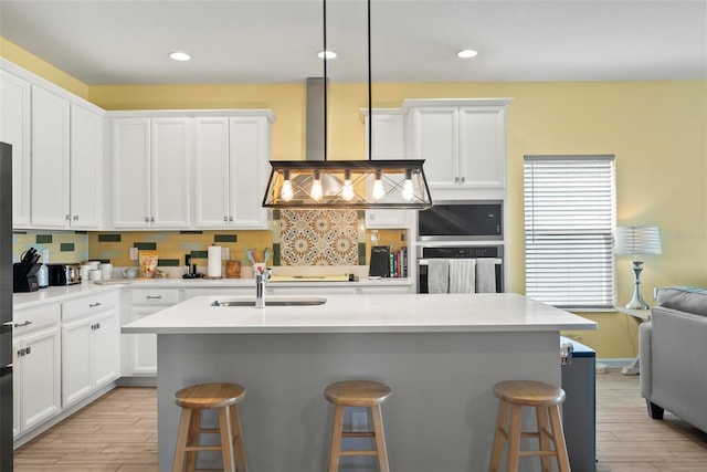 kitchen featuring a kitchen bar, a kitchen island with sink, sink, and oven