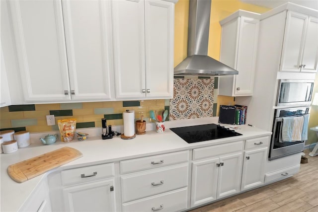 kitchen with white cabinets, oven, wall chimney exhaust hood, black electric cooktop, and tasteful backsplash