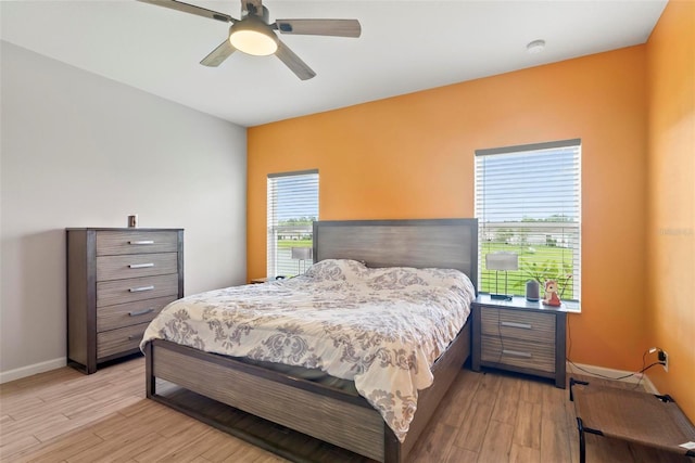 bedroom featuring ceiling fan, light wood-type flooring, and multiple windows