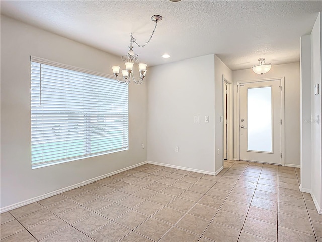 interior space with an inviting chandelier, light tile patterned floors, and a textured ceiling