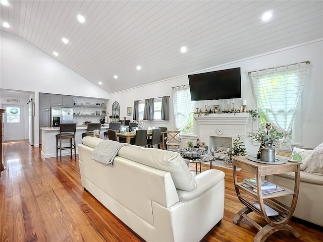 living room featuring light hardwood / wood-style floors, wooden ceiling, and high vaulted ceiling