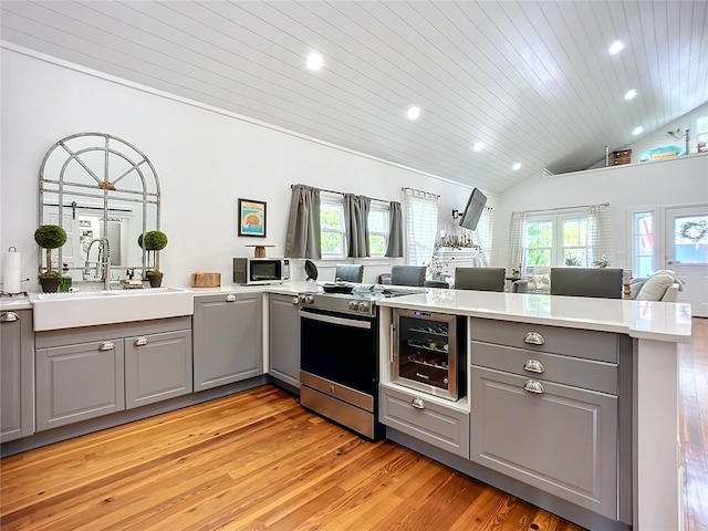 kitchen featuring gray cabinetry, kitchen peninsula, light hardwood / wood-style floors, stainless steel range oven, and wood ceiling