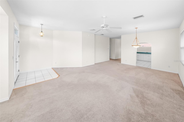 empty room with visible vents, ceiling fan, and light carpet