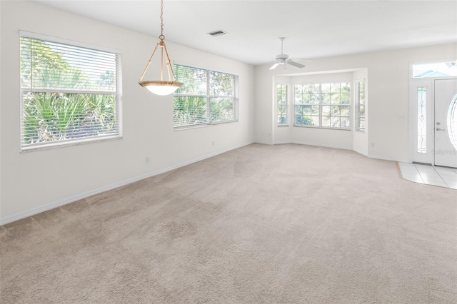 spare room featuring light carpet, baseboards, visible vents, and a healthy amount of sunlight