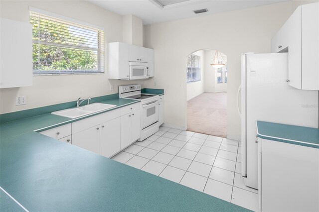 kitchen with arched walkways, light tile patterned floors, white cabinetry, a sink, and white appliances