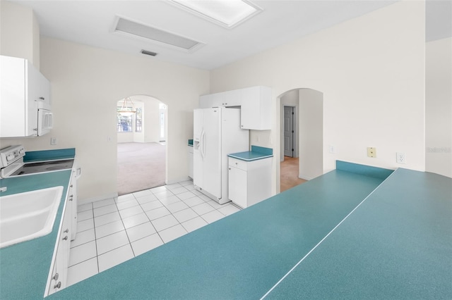 kitchen featuring arched walkways, white appliances, white cabinetry, and a sink