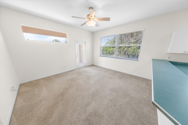 spare room with light colored carpet, a healthy amount of sunlight, and ceiling fan