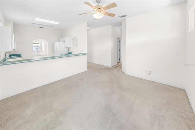 unfurnished room with arched walkways, ceiling fan, light carpet, a sink, and visible vents