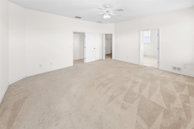 unfurnished bedroom featuring light carpet, visible vents, a walk in closet, and ensuite bathroom