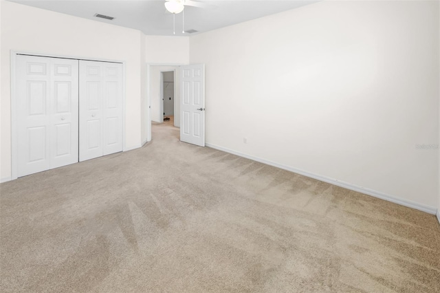 unfurnished bedroom with baseboards, visible vents, light colored carpet, ceiling fan, and a closet