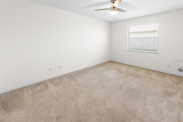 spare room featuring baseboards, a ceiling fan, and light colored carpet