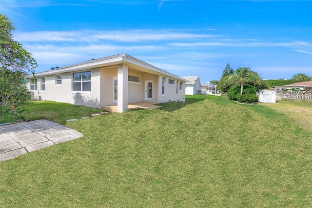 back of property with stucco siding, fence, a lawn, and a patio