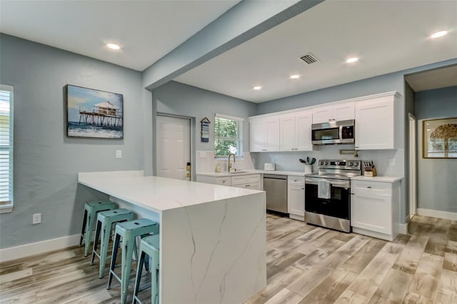 kitchen featuring sink, light hardwood / wood-style flooring, white cabinets, and appliances with stainless steel finishes