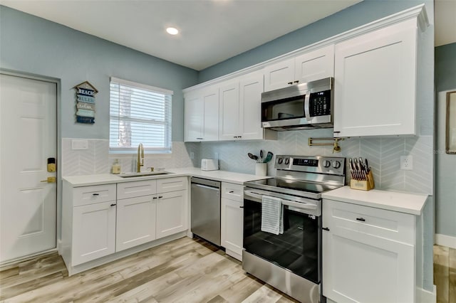 kitchen with light hardwood / wood-style floors, white cabinets, tasteful backsplash, and stainless steel appliances