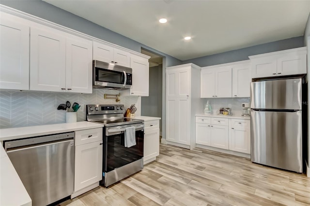 kitchen with appliances with stainless steel finishes, white cabinetry, tasteful backsplash, and light wood-type flooring