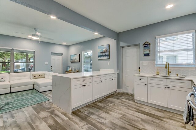 kitchen with white cabinets, sink, backsplash, and light wood-type flooring