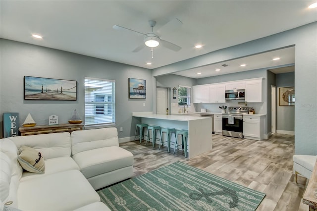 living room with ceiling fan, light hardwood / wood-style floors, and sink