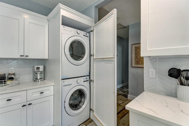 clothes washing area with hardwood / wood-style floors and stacked washer and clothes dryer