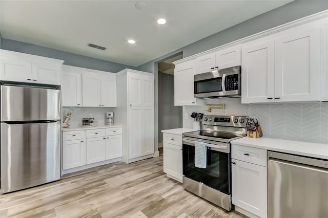 kitchen featuring stainless steel appliances, light wood-type flooring, white cabinetry, and backsplash