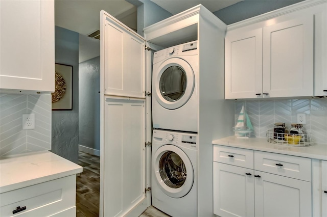 laundry room featuring stacked washer and clothes dryer, cabinets, and hardwood / wood-style flooring