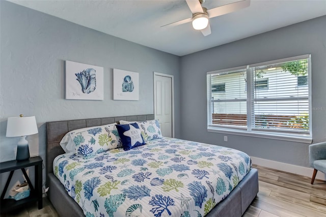 bedroom with a closet, wood-type flooring, multiple windows, and ceiling fan